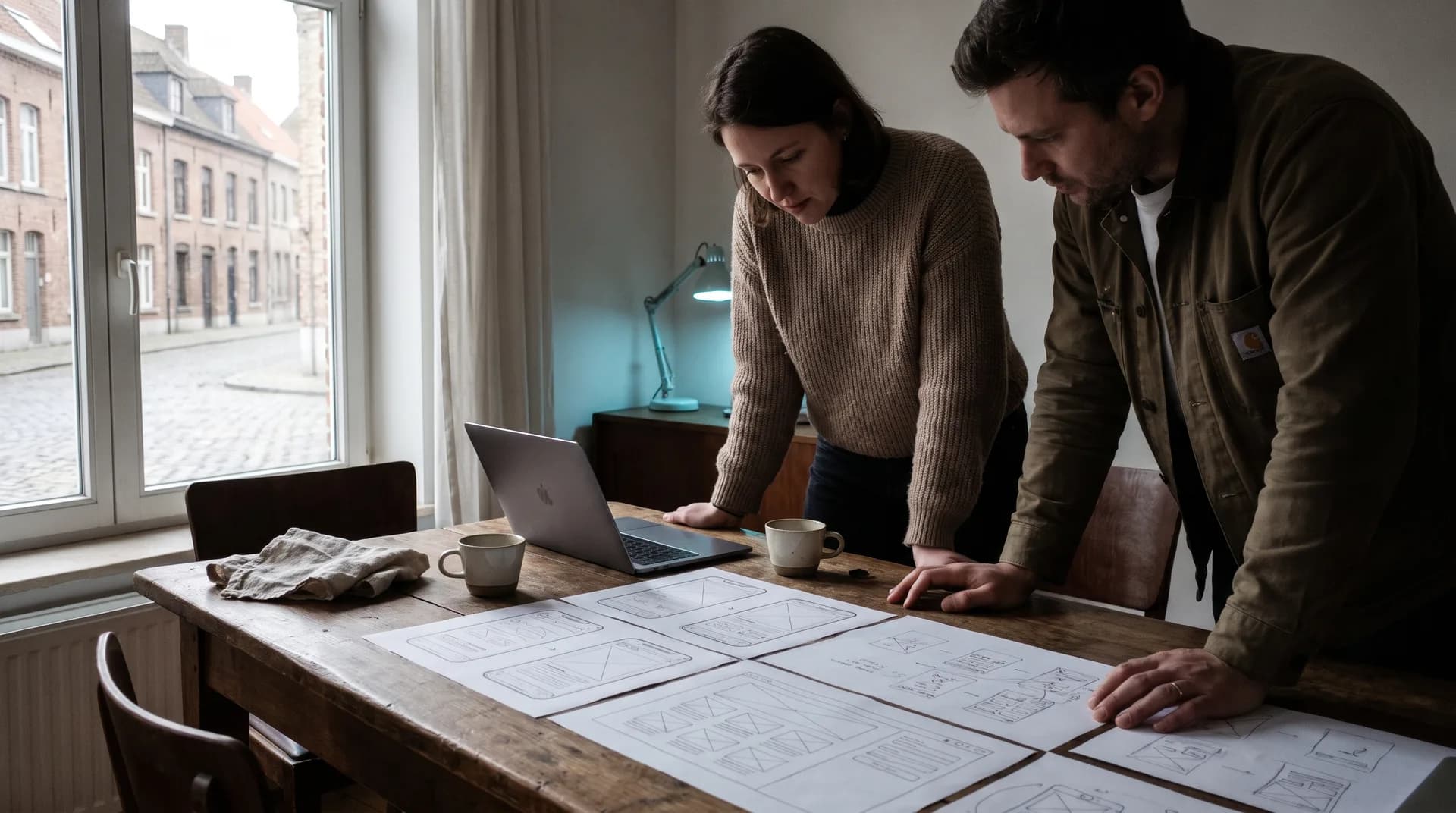 Webdesigner en ondernemer bespreken samen een websiteontwerp aan een werktafel